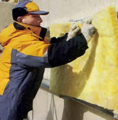 Мастер по отделке фасадов устанавливает теплоизоляционный слой