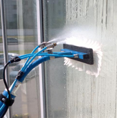 Специалисты очищают стекла с помощью гидроструйного аппарата