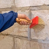 Специалист очищает стены перед отделочными работами