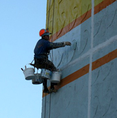 Промышленные альпинисты выполняют покраску фасада жилого дома