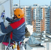 Нанесение промышленными альпинистами нового покрытия на фасад дома